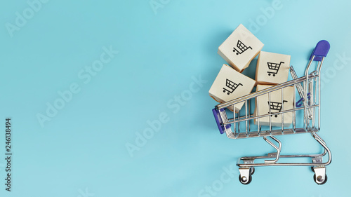 Boxes in a shopping cart on blue background. Concept: online shopping, e commerce and delivery of goods. Copy space. photo