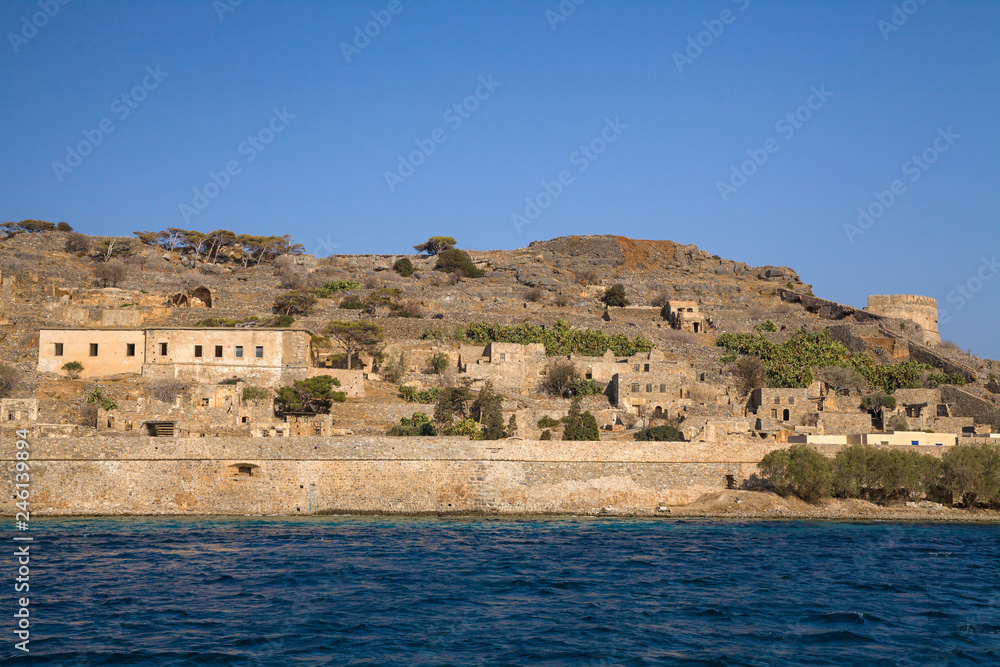 Cruise to the island of Spinalonga. Small boat on the blue lagoon. Spinalonga fortress on the island of Crete, Greece. Architecture on the island.