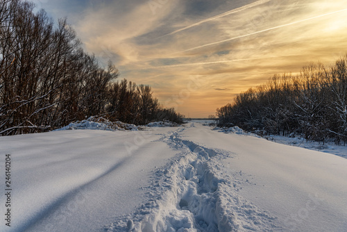 Path in the snow showing footsteps in winter time in sunset, low temperature, in the forest