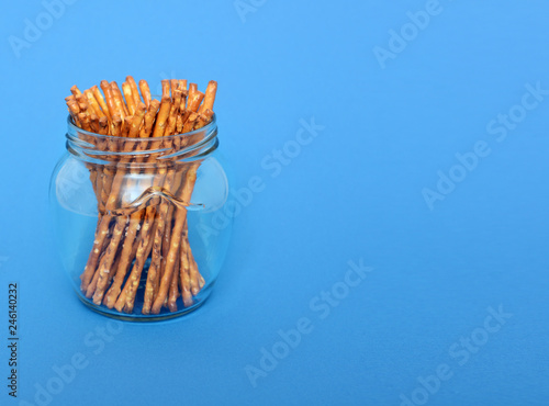 many salted sticks in glass jar over a blue background