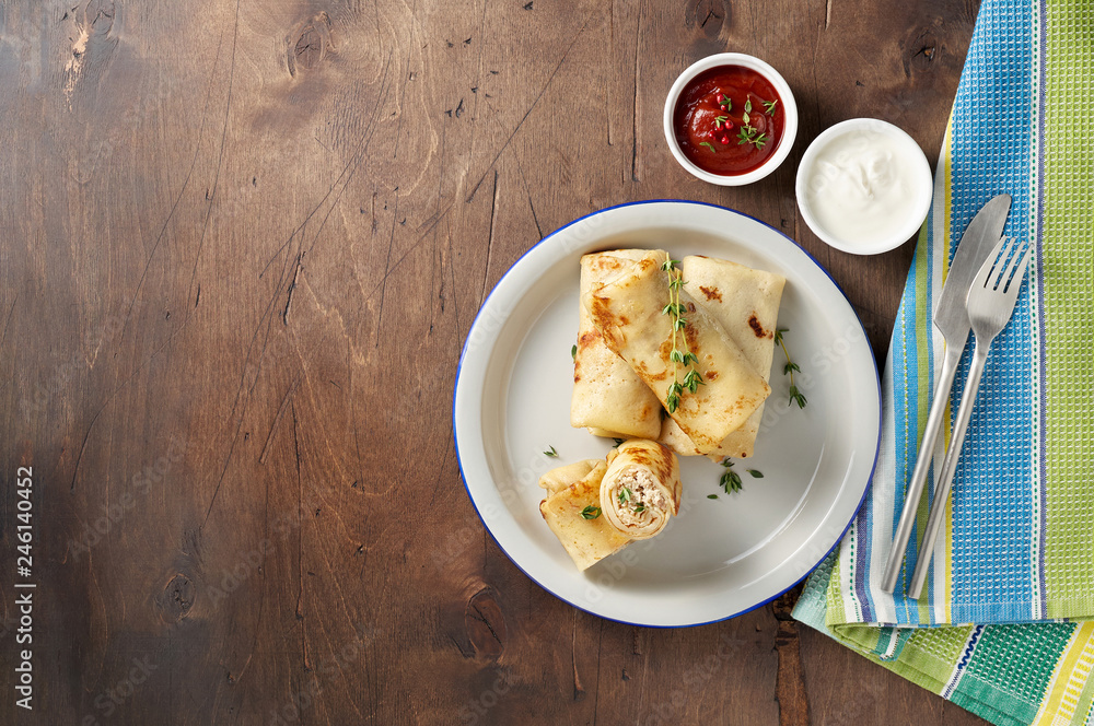 Savory crepe rolls with ground meat filling served with sour cream and tomato sauce Savory crepe rolls with ground meat filling served with sour cream and tomato sauce