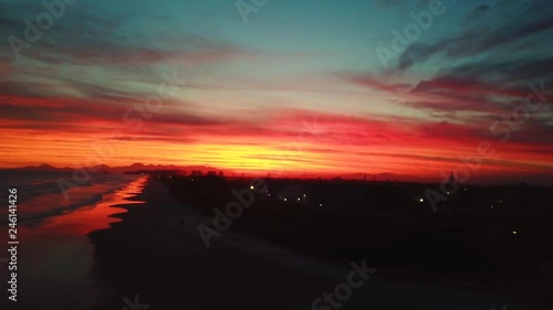 Icredible aerial sliding shot of red color sky in sunset on an ocean beach photo