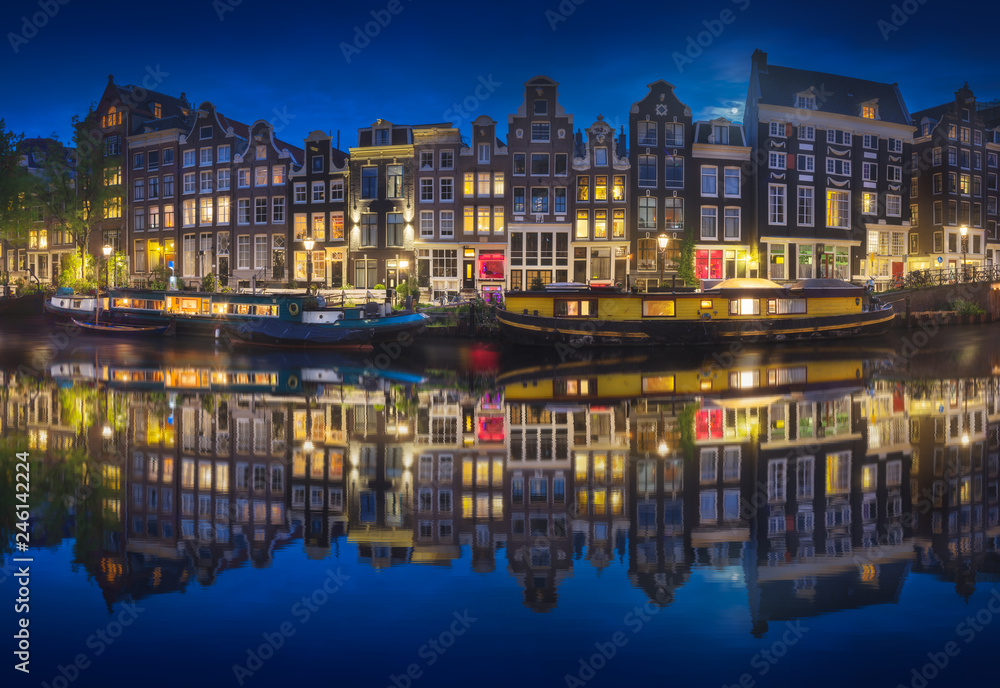 Cityscape of Amsterdam at night with reflection of buildings on water