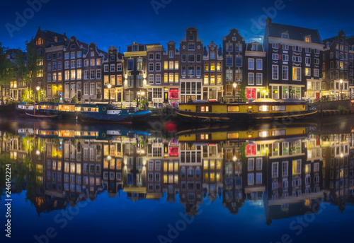 Cityscape of Amsterdam at night with reflection of buildings on water