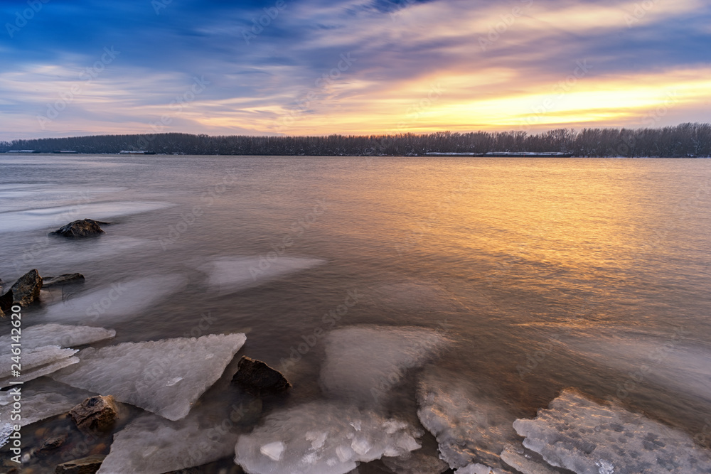 Winter sunset at Danube River in Europe covered with ice at low temperatures 