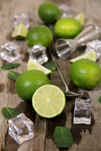 Lime, mint, ice with bar utensils on wooden table. Ingredients for Mojito cocktail making.