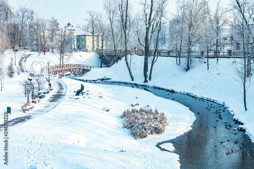 Fototapeta Naklejka Na Ścianę i Meble -  panorama of a snowy city park with a river and a bridge
