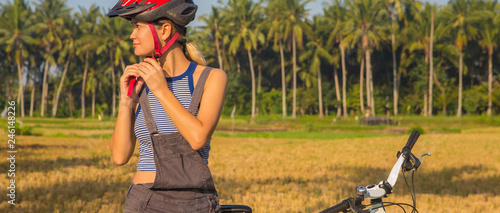 Cyclist woman putting bike helmet on - head protection on outdoor sport activiy. photo