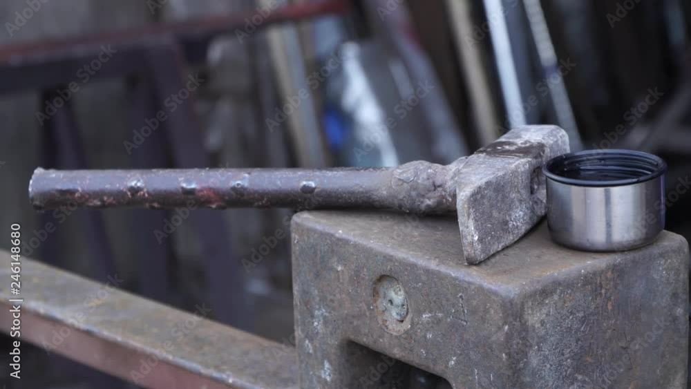 Hammer, anvil and metal cup with hot tea Hammer, anvil and metal cup with hot tea