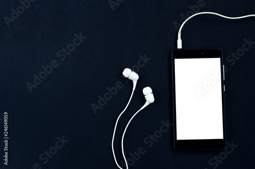 Smartphone and headphones on a black background.  Top view, space for text photo