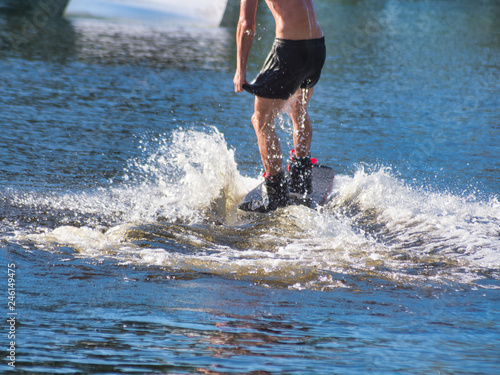 Canvas Print A wakeboarder, a young man on a wakeboard rides on the water in shorts without a t-shirt