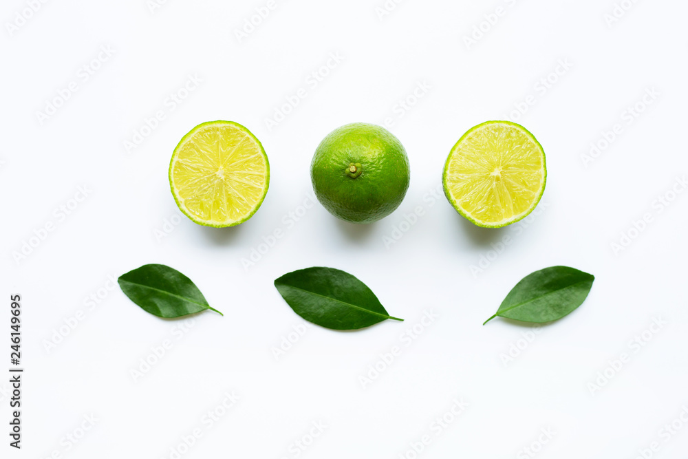 Ripe limes with green leaves on white.