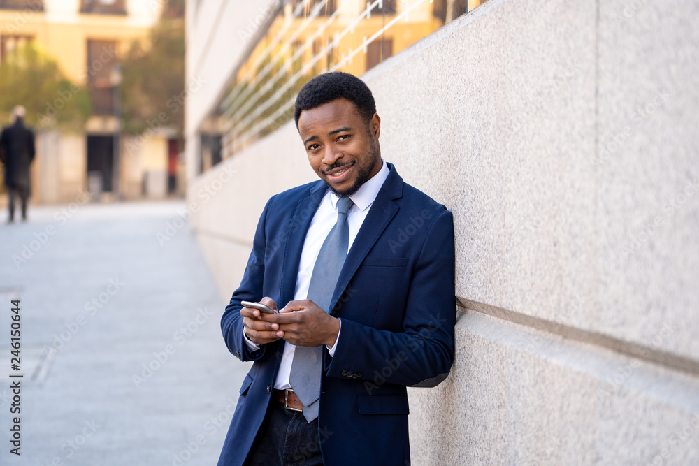 Young handsome businessman using mobile phone app sending message outside office in urban city Young handsome businessman using mobile phone app sending message outside office in urban city