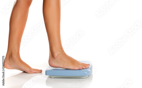Young woman standing on a scale on white background