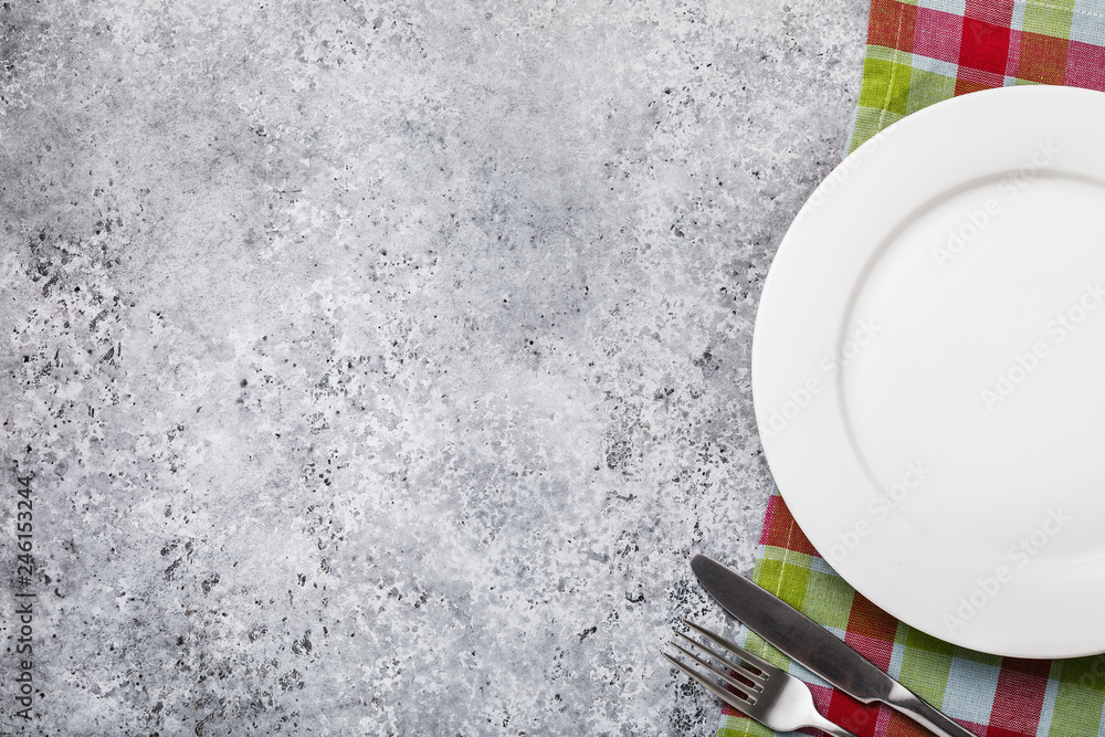 Fork, knife and white plate on the right side of the table with a ...