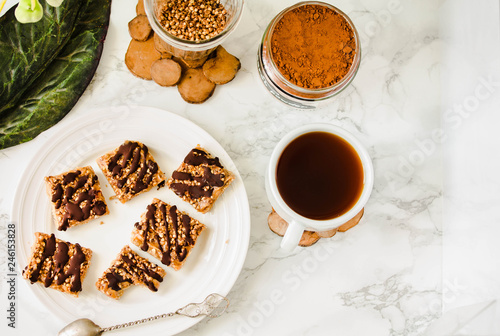 Granola bar with date caramel and chocolate. Healthy sweet dessert snack. Cereal granola bar with nuts  fruit and berries on a white marble table. Top view. A cup of coffee. Healthy breakfast.