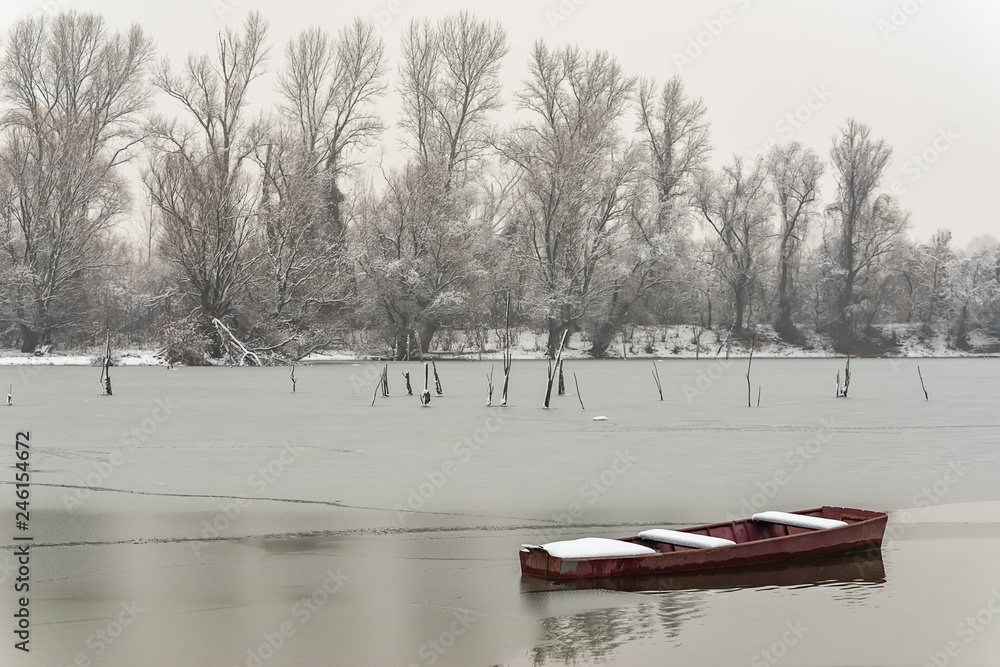 Naklejka premium Beautiful frozen river. A boats covered with snow.