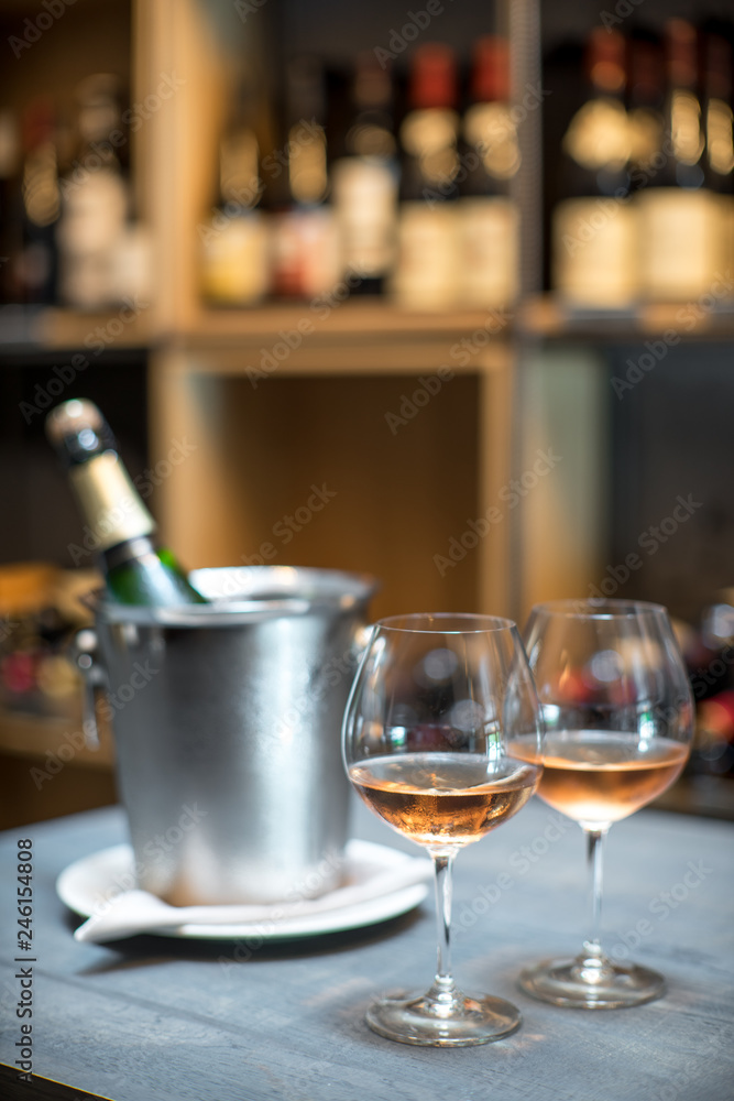 A bottle of champagne in a bucket with ice on the table. Two cold glasses of sparkling wine. A bottle of champagne in a bucket with ice on the table. Two cold glasses of sparkling wine.