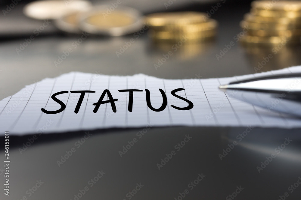 Status auf einem Zettel mit Stift vor Geldmünzen Status auf einem Zettel mit Stift vor Geldmünzen