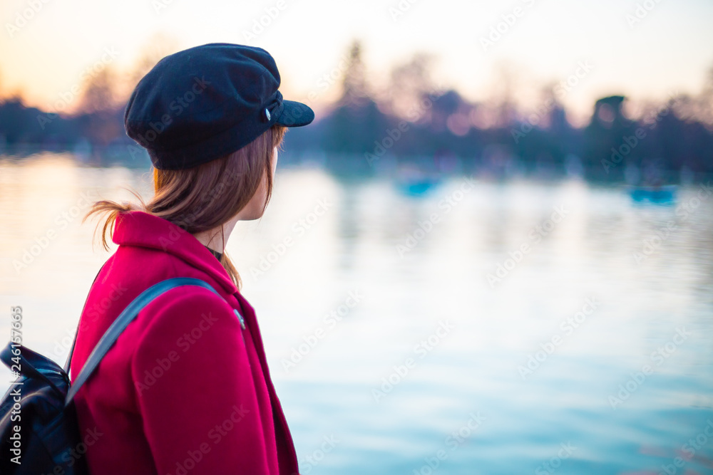Young woman with stylish clothes looking at a lake at sunset Young woman with stylish clothes looking at a lake at sunset