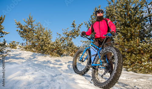 Man riding a mountain bike with big fat tires and helmet on a snow. Fat bike.