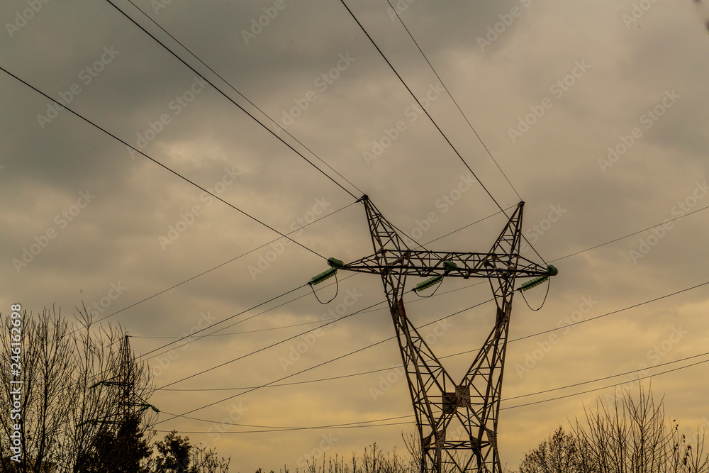 an electric pole with high voltage cables in the background of a dramatic sky with beautiful clouds. power transmission. electrical cable distribution.