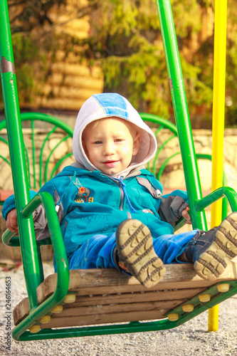 Cute 3 year old boy excitedly plays on playground outdoors a cool spring day. © Evgeniy