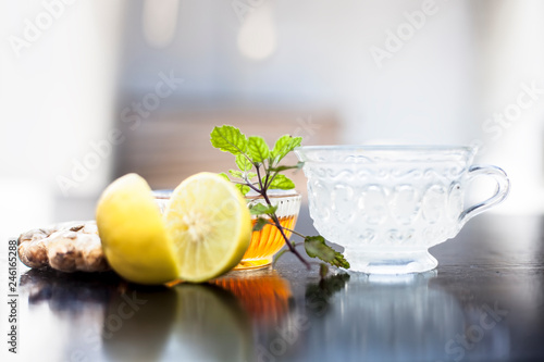 Close up of honey tea isolated on wooden surface i.e. Honey,lemon juice, water, ginger and some mint leaves all mixed together in a transparent glass cup.