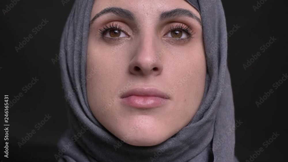 Close-up portrait of female hands doing make-up for muslim woman in hijab watching upwards on black background. Close-up portrait of female hands doing make-up for muslim woman in hijab watching upwards on black background.