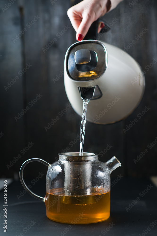 chef pours tea into cups, black wooden background