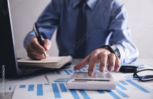 Businessman working in office and using calculator.