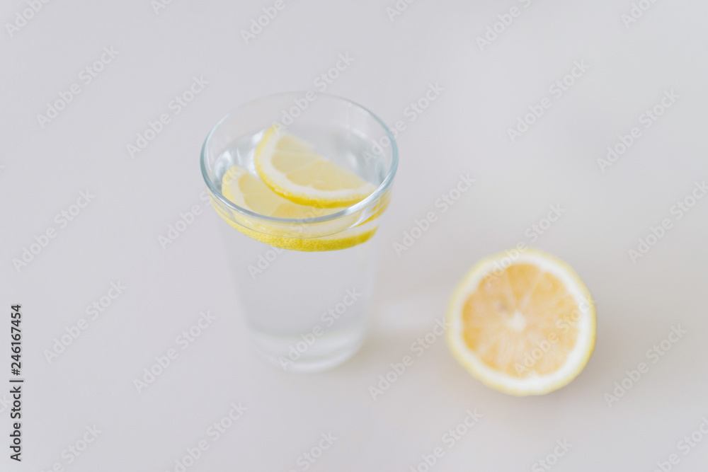 A glass of fresh cool water with lemon slices on a white background A glass of fresh cool water with lemon slices on a white background