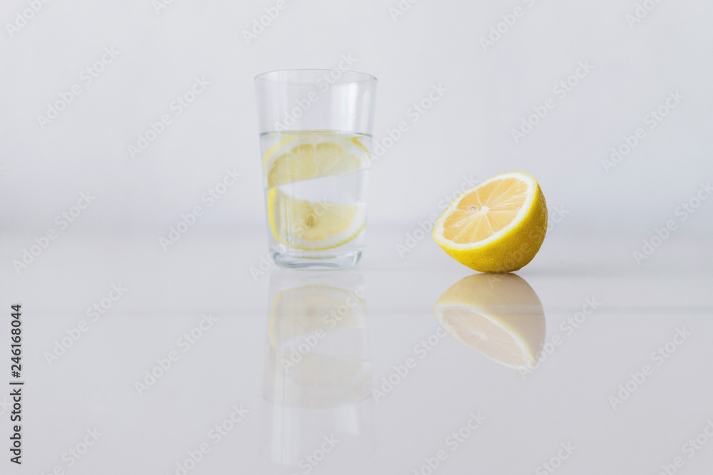 A glass of fresh cool water with lemon slices on a white background A glass of fresh cool water with lemon slices on a white background