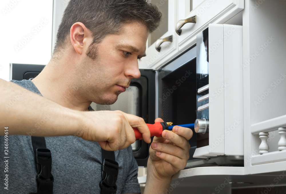 Male technician repairing microwave oven at home. Male technician repairing microwave oven at home.