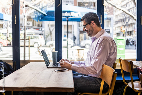 Middle aged businessman in a coffee shop with his computer