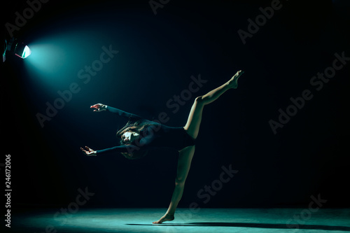Young female ballet dancer dancing on neon lights studio background. Ballerina project with caucasian model. The ballet, dance, art, contemporary, choreography concept