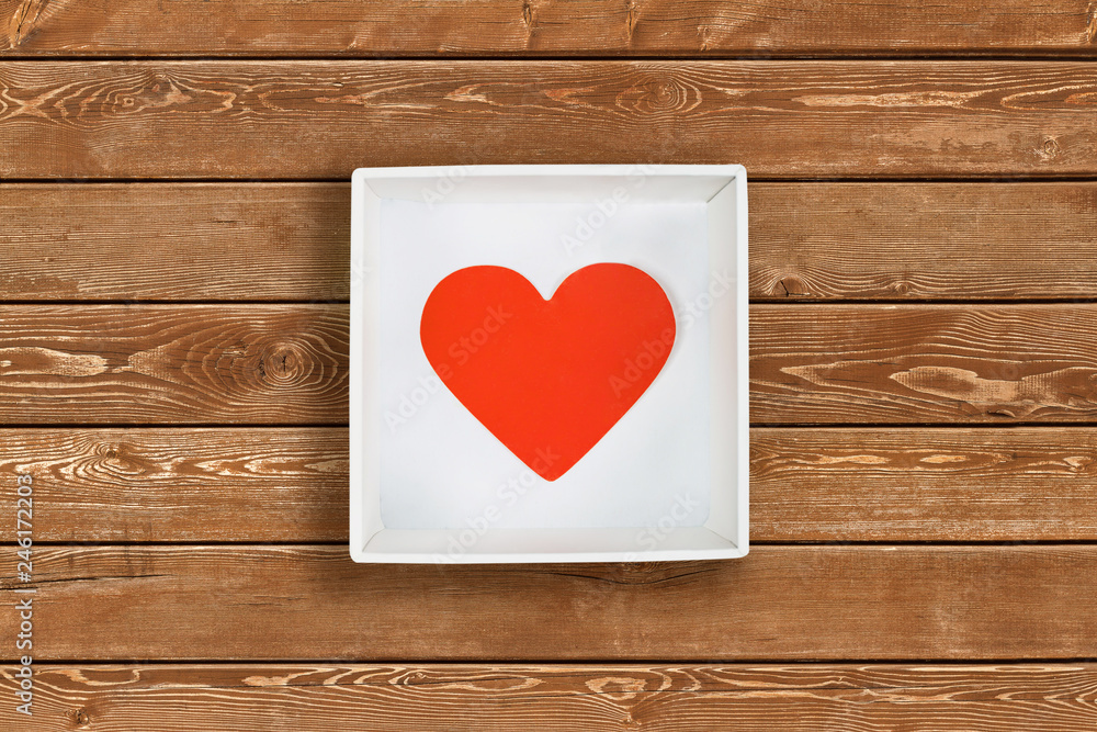 Red paper heart in white cardboard box on wooden wall background. Flat lay. Top view. Valentine's Day concept Red paper heart in white cardboard box on wooden wall background. Flat lay. Top view. Valentine's Day concept