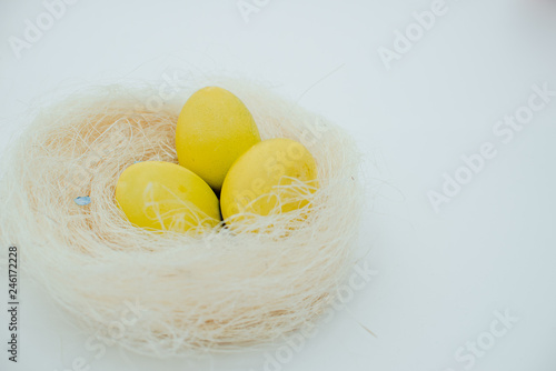 Fototapeta Naklejka Na Ścianę i Meble -  Yellow Easter eggs in a nest of grass. Eggs in a  nest basket top view.  Easter composition.Top view several objects horizontal view red background. Still life eggs White background.