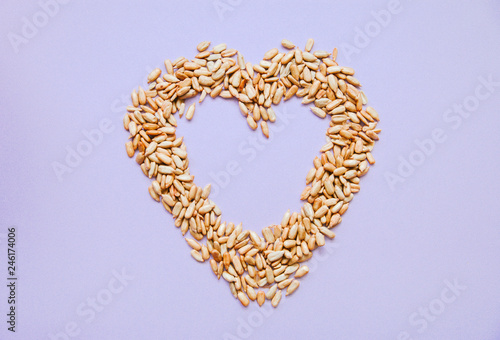 heart of sunflower seeds on purple background  top view flat lay