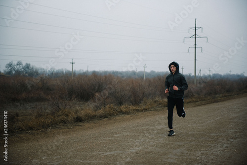 A man runs in headphones on the road. Stroke in pants and sneakers