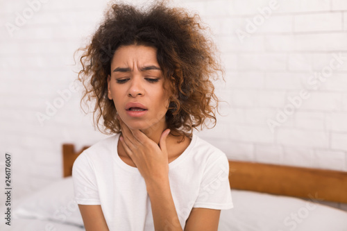 African-american woman with sore throat sitting on bed photo