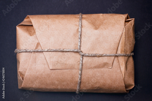 Craft wrapped package on black background. Parcel with hemp cord. 