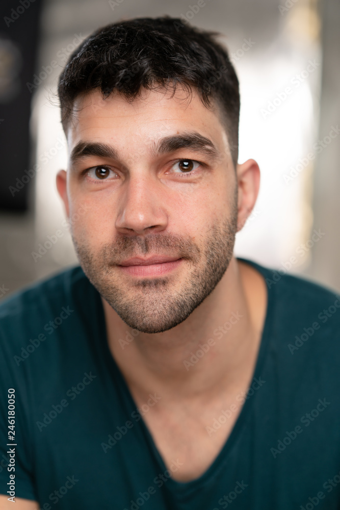 Handsome caucasian white male with black short hair and stubble with blue t shirt with a smirk Handsome caucasian white male with black short hair and stubble with blue t shirt with a smirk