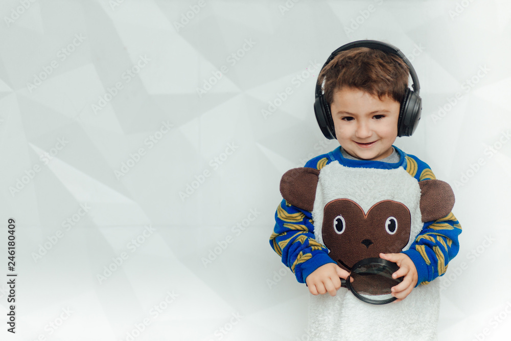 A pretty little boy with headphones and smiling. Fashion home shot. Childhood. Kid's fashion. Kids and technology concept, happy kids listen music. child kid smile and wearing headphone to enjoyed A pretty little boy with headphones and smiling. Fashion home shot. Childhood. Kid's fashion. Kids and technology concept, happy kids listen music. child kid smile and wearing headphone to enjoyed