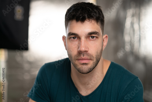 Handsome caucasian white male with black short hair and stubble with blue t shirt,looking serious
