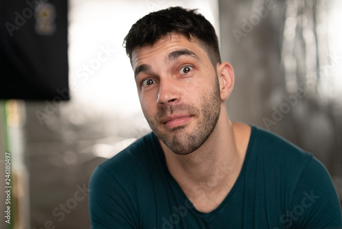 Handsome caucasian white male with black short hair and stubble with blue t shirt, silly face