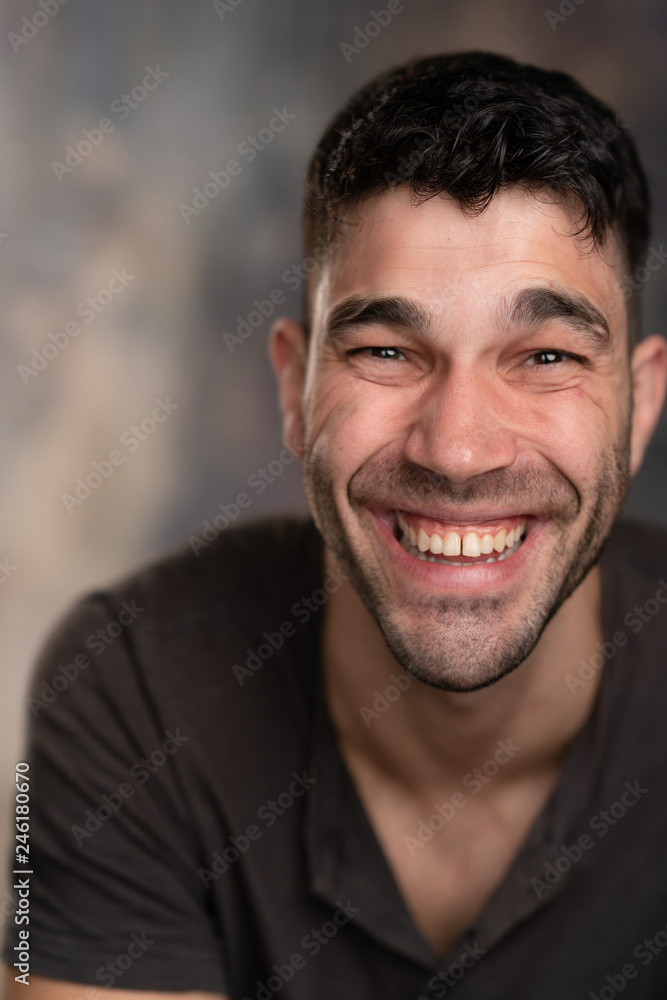 Handsome caucasian white male with black short hair and stubble with brown t shirt laughing hilariously Handsome caucasian white male with black short hair and stubble with brown t shirt laughing hilariously