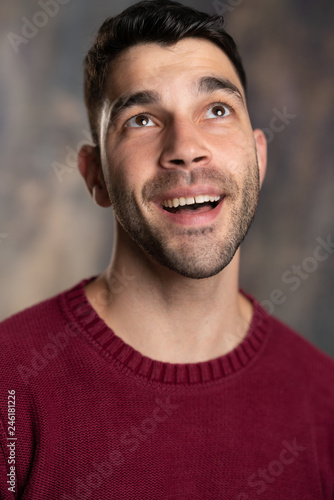 Handsome caucasian white male with black short hair and stubble and burgundy sweater jersey looking up