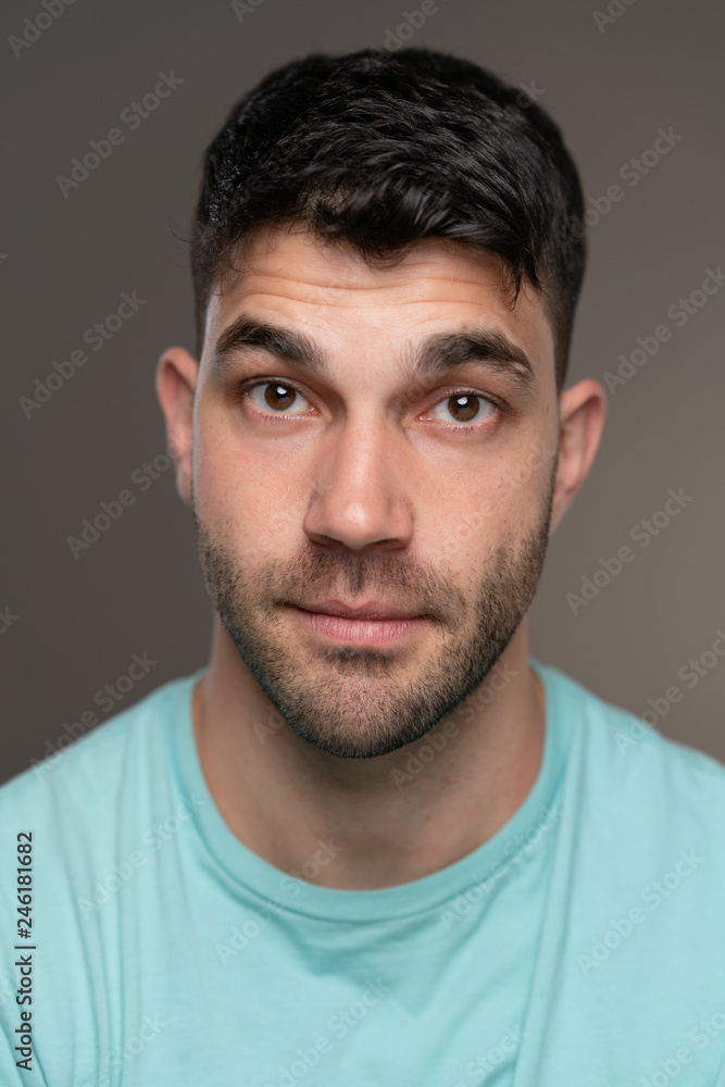 Handsome caucasian white male with black short hair and stubble with light blue t shirt Handsome caucasian white male with black short hair and stubble with light blue t shirt
