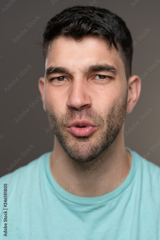 Handsome caucasian white male with black short hair and stubble with light blue t shirt impressed Handsome caucasian white male with black short hair and stubble with light blue t shirt impressed